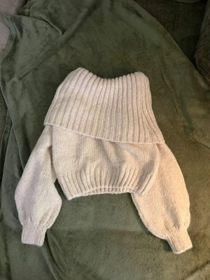 Stickad offshoulder tröja  - Superfin offwhite stickad tröja med bred, ribbad offshouöder och ballongärmar. Tröjan har ribbade muddar vid ärmslut och midja, och är gjord i ett mjukt, tjockt material. Perfekt för kyliga dagar och snygg till både jeans och kjol. Använd ett fåtal gånger men utan defekter.