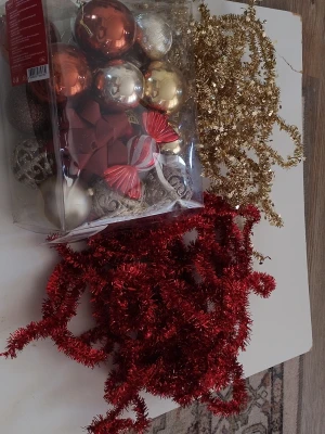 Julgranspynt i rött, guld och silver - Ett set med julgranspynt som innehåller kulor i rött, guld och silver, samt glittrande girlander i rött och guld. Perfekt för att dekorera granen eller hemmet under julen. Innehåller även dekorativa rosetter och polkagrisar i plast.