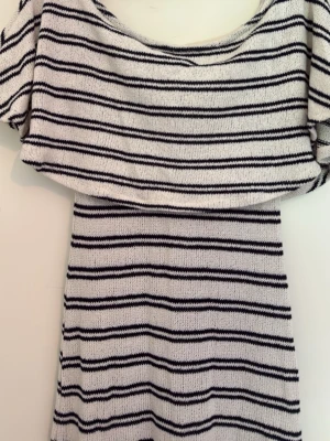 Randig off shoulder  långklänning från Gina Tricot - Virkad off shoulder-klänning med ränder i maxi-längd. Den har volang upptill, figurnära passform och normal storlek. Stretchig vilket gör att den passar storlek S och M 