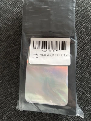 Svarta påsar 8x13cm Rimiko  - Säljer ett paket med 100 holografiska-svarta påsar från Rimiko, storlek 8x13 cm. Påsarna är tillverkade i plast och har en slät, gl obvious lands finish. Perfekta för småförvaring eller organisering.
