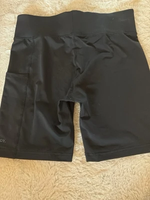 Svarta tränigsshorts från newbody - Säljer svarta träningsshorts från newbody. Använda några gånger. En ficka på vänster sida där mobilen passar i. Gummi längst ner vid benen så att shortsen inte åker upp och ner. 