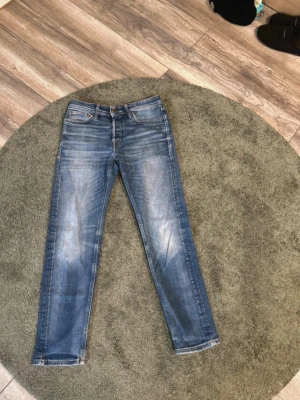 Blå Jack & Jones Jenas - Snygga blå jeans med lätt slitna detaljer och klassisk femficksdesign. Storlek: 30/30. 97 cm längd,38 bredd i midjan ,18 cm bredd vid knät 