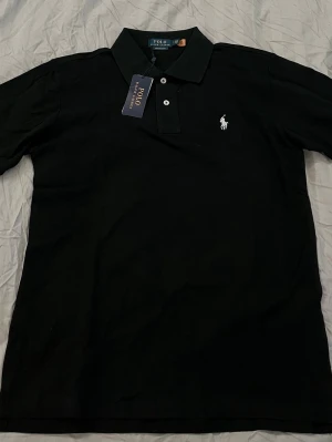 Svart pike från Polo Ralph Lauren - Klassisk svart polotopp från Polo Ralph Lauren, nyskick. Hör av dig vid funderingar eller frågor!