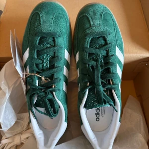 Adidas Gazelle i grönt mocka - Snygga Adidas Gazelle sneakers i grönt mocka med vita detaljer och snörning. New with tags och aldrig använda!