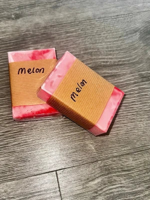 Melontvål  - Tvålar med fräsch melondoft, handgjorda på sheasmörbas från Greenum. Färgen är rosa och röd med marmorerad effekt. Kommer i rektangulär form och inslagen i papp. Perfekt för dig som gillar söta dofter och veganska ingredienser.