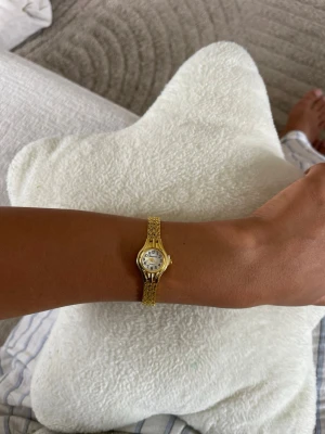 Justerbar Elegant guldfärgad klocka, lätt att justera med en nål.📌  - 19cm Stilren guldfärgad klocka med smalt länkarmband och rund vit urtavla. Klassisk design med tydliga svarta siffror och små visare. Perfekt accessoar för dig som gillar en tidlös look.