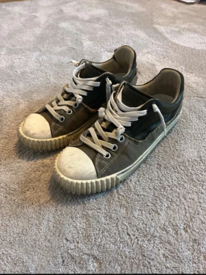 Margiela evolution low  - Säljer dessa svinfeta Maison margiela evolution i storlek 41, de passar även 42. Skorna är i ganska dåligt skick då de använts mycket men det ger de bara mer karaktär enligt mig då modellen är ganska sliten från början.                                                         En knapp saknas(bild 5) Ett hål söm har gått upp(bild 6) Låda saknas Annars är skorna i topp skick och har många år av användning kvar i sig!