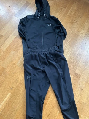 Under armour tracksuit   - Säljer ett par tränings under byxor tillsammans med en under armour jacka dom passar väldigt bra med varandra och har väldigt fin passform och säljs till väldigt bra pris. Storlek på jacka är XS och storlek på byxor är S men passar bra på XS 