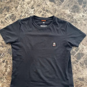 Parajumpers T-shirt - En knappt använd svart t-shirt från Parajumpers i nyskick. Digitalt kvitto från Parajumpers officiella hemsida och QR-kod finns som autentisering. Något större i storleken, så kan även passa dig som normaltvis har S. Ordinariepris ligger på ca 1000-1200kr.