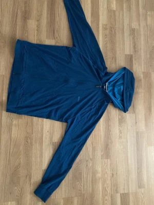 Blå hoodie från BOSS Homewear - Snygg blå hoodie från BOSS Homewear med dragkedja framtill och två fickor. Tillverkad i mjukt material och har en klassisk huva med kontrastfärgad kant. Perfekt för chill dagar eller när du vill ha en clean look.