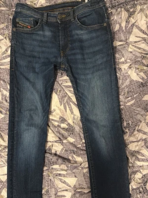 Diesel jeans slimfit - Snygga mörkblå slim fit jeans med lätt slitning på låren och knäna. Klassisk femficksmodell med raka ben och kontrastsömmar. Jeansen har en modern tvätt och passar perfekt till en avslappnad stil.