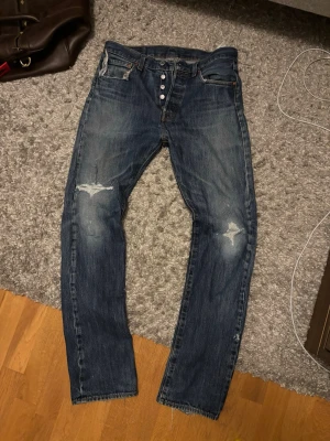 Levi's blå jeans - Riktigt snygga Levis 501:or, med schyssta fades och slitningar, särskilt heelbitsen. Inga hål, utan allt är lagat. Längden är 34, men funkar bra som 32 också. Hör av vid funderingar!