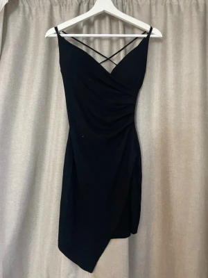 Svart omlottklänning med smala band - Svart omlott klänning. Sneskuren. Har som en insydd bh. Köpt på en marknad i italien.