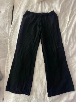 Svarta linnebyxor lågmidjade - Säljer ett par svarta linnebyxor med avslappnad passform och raka ben. Byxorna har resår i midjan för extra komfort och är tillverkade i ett lätt och luftigt linnematerial. Perfekta för en chill och stilren look.