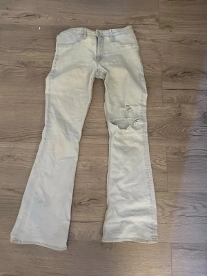 Ljusblå lågmidjade bootcut jeans - Ljusblå, lågmidjade bootcut jeans med slitningar på ena benet. 
