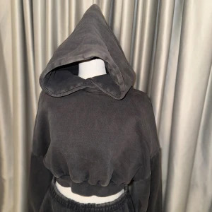Entire Studios Mörkgrå croppad hoodie - Säljer en mörkgrå croppad hoodie med stor huva och långa ärmar. Materialet är bomull. Perfekt för en chill och stilren outfit.