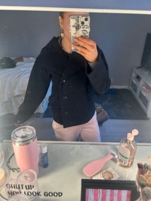 Mörkblå kappa från gina  - Snygg mörkblå rock med dubbelknäppning och bred krage. Rocken har en rak passform och är tillverkad i ett tjockare tyg som passar perfekt för kyligare dagar. Stilen är klassisk men ändå modern, vilket gör den enkel att matcha med olika outfits.