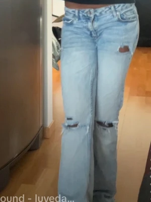 Ljusblå slitna bootcut jeans - Säljer ett par ljusblå bootcut jeans med slitningar och hål på knäna. de har ett hål vid innerbenet,o lite rivet vid rumpan, går nog att sy (vilket jag kan skicka bild på) ! strlk 158-164 i barnstorlek men passar XS 