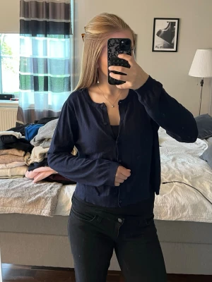 Mörkblå cardigan med knappar - Mörkblå cardigan med rund halsringning och knäppning framtill. OBS! sitter som en S/M