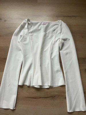 Vit långärmad topp med fyrkantig ringning - Trendig vit långärmad topp från Gina Tricot med snygg fyrkantig ringning och figurnära passform. Perfekt att styla med jeans eller kjol för en clean look. I storlek 158/162 🥰💗