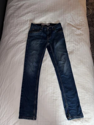 Mörkblå raka jeans från Levi's - Säljer ett par mörkblå jeans från Levi's med klassisk femficksdesign och raka ben. Jeansen har snygga slitningar framtill och är tillverkade i bomull med lite stretch för extra komfort. Perfekta till en avslappnad stil.