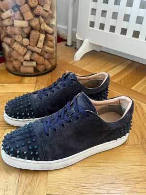 Mörkblåa sneakers med nitar - Ett par unika mörkblå Christian Louboutin skor i storlek 45. Det finns tecken på användning på sulorna och så saknas det två nitar (visas på bilderna). Skriv för funderingar.