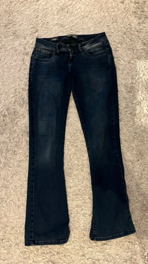 Mörkblå bootcut jeans - Snygga mörkblå low waist bootcut jeans med klassisk femficksdesign och lätt slitning framtill. Jeansen har normal midja och är tillverkade i stretchigt denimtyg för en bekväm passform. Perfekta för dig som gillar en tidlös och avslappnad stil.