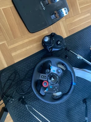 Logitech G29 Racing ratt, pedaler - Säljer en Logitech G29 racing ratt med pedaler och växelspak. Ratten har svart läderklädsel, blå markering upptill och PlayStation-knappar. Pedalerna är i metall och plast. Perfekt för racing på PlayStation eller PC. OBS. Växelspak är redan såld.
