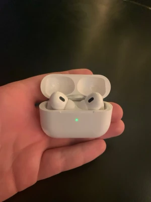 Apple AirPods Pro med laddningsetui - Trådlösa Apple AirPods Pro i vit färg med tillhörande laddningsetui. Hörlurarna har en stilren och kompakt design med silikonproppar och brusreducering. Perfekta för musik, samtal och träning. Laddningsetuiet är också vitt och har en LED-indikator på framsidan. Inte riktiga helt nya kommer med laddare Lightning