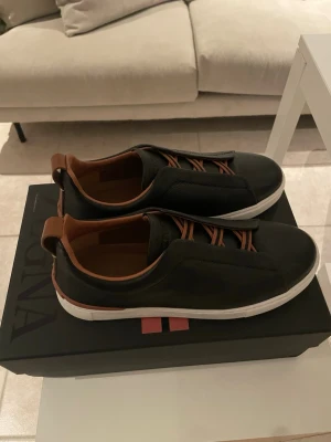 Zegna Skor - Zegna triple stitch sneakers i utmärkt skick. Storlek 42. Smått sönder där bak men går lätt att limma fast, syns dock inte om man låter den vara. 