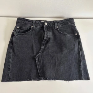 Svart jeanskjol med rå kant - Säljer en svart jeanskjol med rå och fransig kant nertill, som jag har sytt om från ett par jeans. Kjolen har en rak passform och synliga sömmar framtill och baktill för en cool, avslappnad look. Storleken är 40, men den är väldigt liten i storleken, skulle säga att den sitter som S
