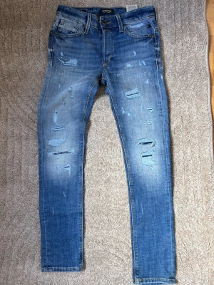 Blå slitna jeans från Jack & Jones -  Hej och välkomna till Liljestrands Nu säljer vi Ett par Jack and Jones jeans i nyskick använda en gång slitningar från fabrik liten storlek därav priset Kom med frågor OSV så hörs vi. MVH Liljestrand
