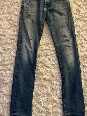 Mörkblå slitna skinny jeans - Säljer ett par mörkblå skinny jeans med slitningar och tvättade detaljer. Jeansen har klassisk femficksmodell, låg midja och smal passform. Perfekta för en avslappnad och trendig look.