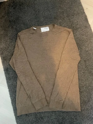 Brun tröja från Selected Homme - Snygg brun långärmad tröja från Selected Homme. Enkel design med rund halsringning och ribbade muddar vid ärmslut och nederkant. Perfekt för en stilren och avslappnad look.