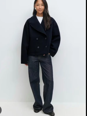 Mörkblå jacka från Gina - Stilren mörkblå skepparkavaj från Gina Tricot med dubbelknäppning och breda slag. Jackan har en boxig passform och är tillverkad i ett kraftigt ullblandat material. Perfekt för dig som gillar minimalistisk och tidlös stil. Aldrig använd.