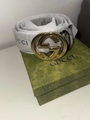 Gucci vitt bälte med guldspänne kvitto finns - Snyggt vitt bälte från Gucci med ikoniskt GG-spänne i guld. Bältet har diskret Gucci-logga längs bandet och är tillverkat i tyg med exklusiv känsla. Perfekt accessoar för att lyfta din outfit.