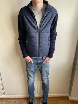 Mörkblå cardiganjacka från Sayless  - Mörkblå cardiganjacka med quiltad framsida och stickade ärmar och rygg. Jackan har dragkedja framtill, ståkrage och två fickor med tryckknapp. Perfekt för lager-på-lager och en stilren look. Priset kan diskuteras vid snabb affär 💨🤝