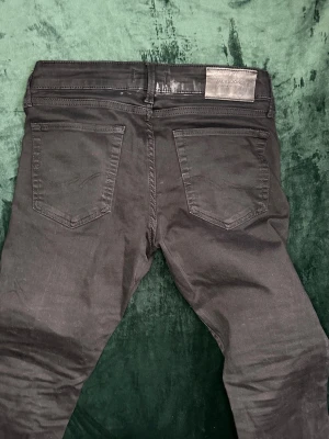  Jack & Jones -  Ett par svarta Jack & Jones jeans som inte används. Passar nog till en helsvart outfit. Har dock ett hål Under vänstra Knät. Pris kan diskuteras. MVH stentorparchive⚓️