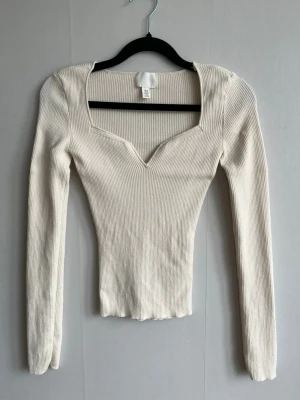 Ribbad vit långärmad topp H&M - Snygg ribbad vit/ljust beige topp från H&M med lång ärm och v-ringad halsringning.