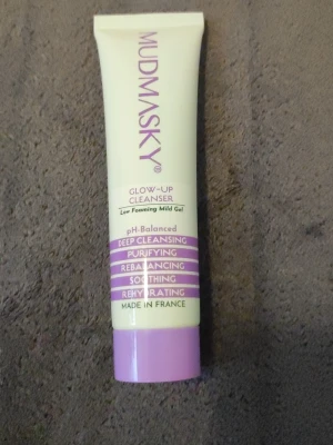 Mudmasky Glow-Up Cleanser gel - Mild rengöringsgel från Mudmasky i en ljusgul tub med lila detaljer. Produkten är pH-balanserad och ger djup rengöring, återfuktning och lugnande effekt. Perfekt för dig som vill ha en skonsam men effektiv ansiktsrengöring.