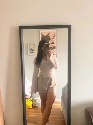 Vit omlottkofta med knytband - Vit omlottkofta med långa ärmar och knytband i midjan. Koftan har en lätt ribbad struktur och ger en avslappnad men ändå trendig look. Perfekt att matcha med shorts eller jeans för en chill outfit. Storlek M men passar S också