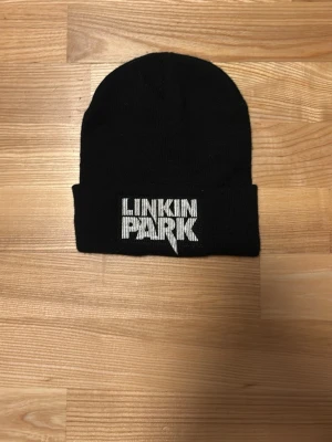 Svart Linkin Park mössa - Säljer en svart mössa med Linkin Park-logga broderad 22 cm lång och 19 cm bred 