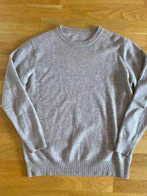 Beige Merinoull tröja Man - Mjuk och stilren beige stickad tröja med rund halsringning och ribbade muddar vid ärmslut och nederkant. Perfekt basplagg i garderoben, enkel att matcha och har en avslappnad passform. Materialet ser ut att vara ull eller en ullmix.Merinoull