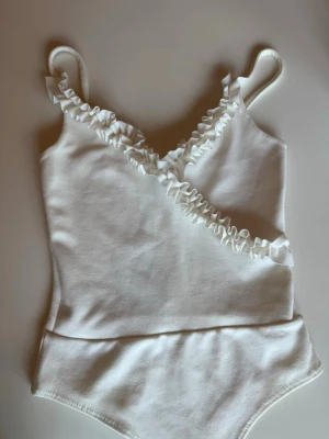Vit body med volangdetalj - Vit body från Gina Tricot i storlek S 🤍 Jättefin och skön att ha på sig. Sitter bra på kroppen och passar till nästan allt – både till jeans och kjol. Perfekt som en enkel topp till vardags eller om man vill klä upp sig lite.  Använd få gånger och i bra skick, pris kan diskuteras!