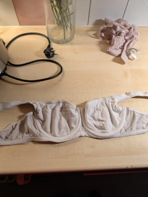 Beige balconette-bh med brodyr - Säljer en beige balconette-bh med bygel och fina broderade detaljer längs axelbanden. Bh:n har lätt vadderade kupor och ger ett lyftande stöd. Materialet känns mjukt och bekvämt mot huden, perfekt för dig som gillar en klassisk och feminin stil.