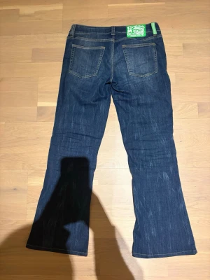 Mörkblå bootcut jeans från Cheap Monday - Säljer ett par mörkblå bootcut jeans från Cheap Monday med klassisk femficksmodell och snygga slitningar framtill. Jeansen har en grön logolapp bak i midjan och kontrastsömmar. Perfekta för dig som gillar retrovibbar och en avslappnad look. Dom är i strlk 31/34💖💖 dom är för stora därför säljer jag dom ! Jag kan absolut gå ner i pris vid snabb affär!🙌🙌🙌🙌