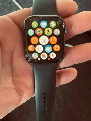 Apple Watch Series 5 44mm svart - Apple Watch Series 5 med 44mm svart aluminiumboett och svart silikonarmband. Klockan har en rektangulär touchskärm och digital krona på sidan. Perfekt för att hålla koll på notiser, träning och hälsa direkt från handleden. Funkar 