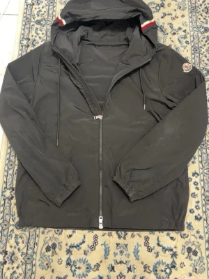 Moncler Windbreaker - Moncler windbreaker, i svart färg, mycket bra skick, fraktas inom 24h vänstra snörret saknar metall i ändan.