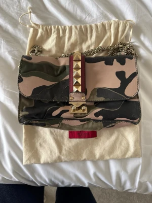 Valentino camo handväska med nitar - Säljer en snygg handväska från Valentino i camomönstrat läder med guldfärgade nitar och kedjerem. 