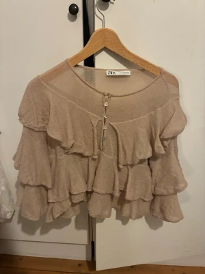 Beige volangblus från Zara - Supersöt beige blus från Zara med flera lager volanger och knappar framtill. 